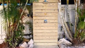 Een houten poort met een decoratief metalen bordje, omringd door rotsen en palmbomen.
