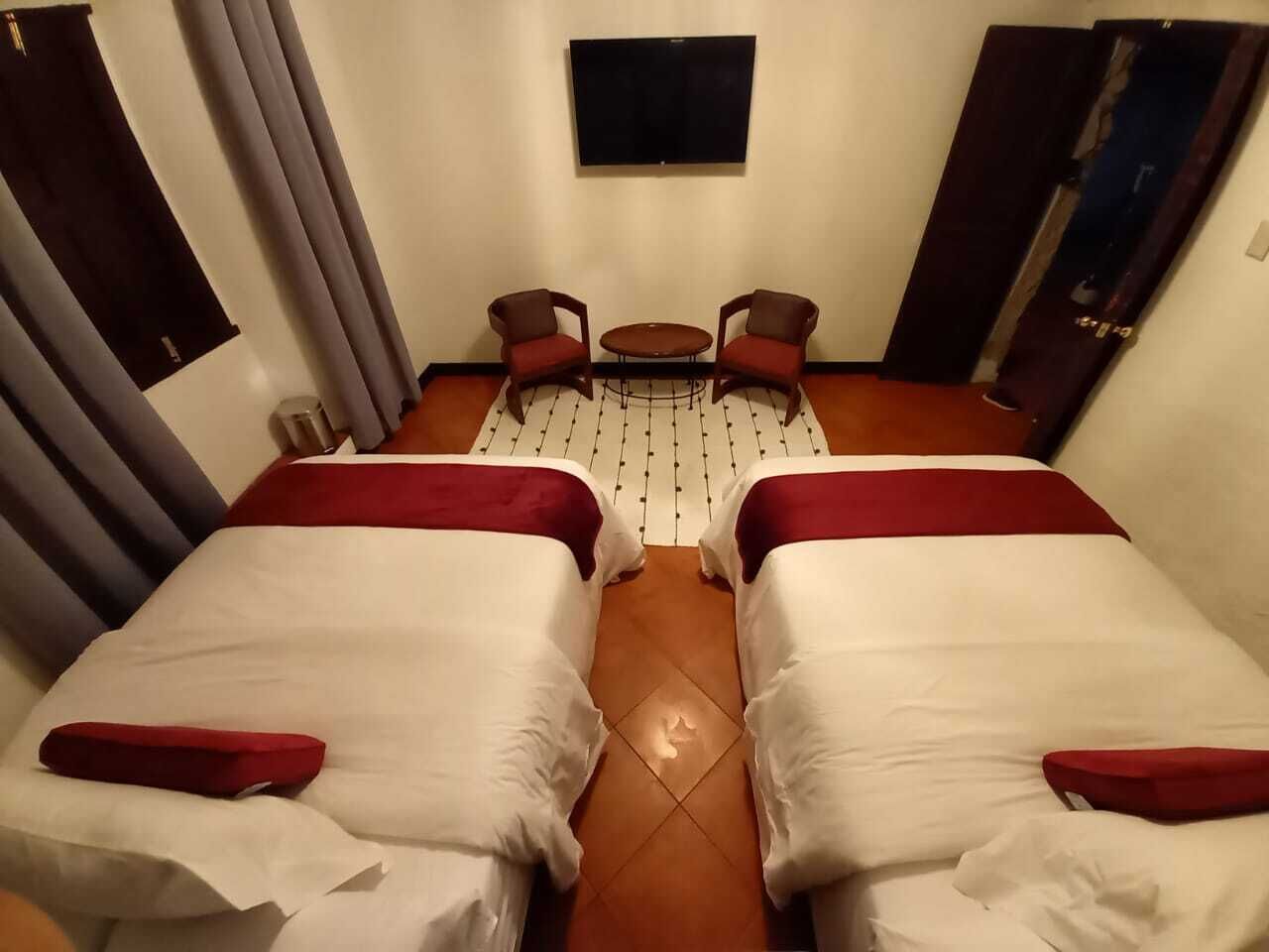 A hotel room with two beds, a small table, and a TV.