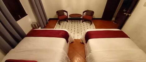 A hotel room with two beds, a small table, and a TV.