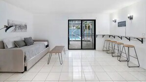 Uma sala de estar moderna e minimalista, com um sofá, uma mesinha e banquetas.