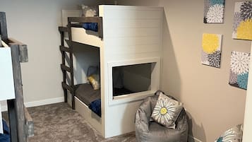 Een stapelbed met een ladder, een slaapzakstoel en een klein bureau.