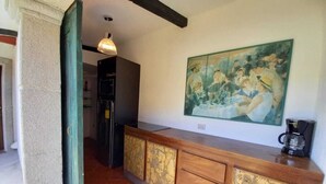 Une cuisine avec un comptoir en bois, un tableau accroché au mur et une machine à café.