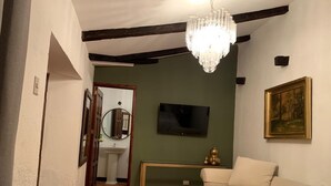 Une chambre à coucher avec un lit, une télévision, un tableau et un lustre.