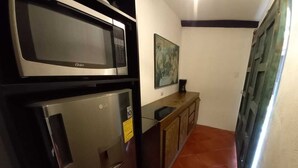 Une cuisine équipée d’un four à micro-ondes et d’un réfrigérateur, d’un meuble en bois et d’un sol carrelé.