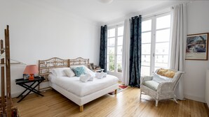 A bedroom with a bed, a chair, a nightstand, and a window with curtains.