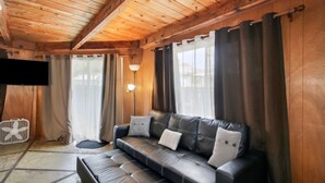 Una habitación acogedora con sofá de cuero, televisor de pantalla plana y techo de madera.