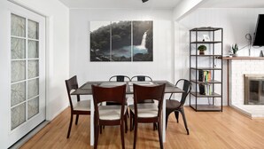 Un área de comedor con una mesa y sillas, una estantería, una chimenea y un ventanal con vidrio esmerilado.