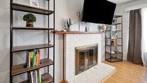 Una sala de estar con chimenea, estanterías, televisor montado y un globo terráqueo.