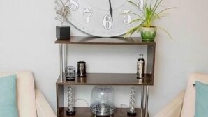 A living room with a large wall clock, two sofas, a plant, and a shelf with decorative items. - <Redrock Views><Near Sedona><Hot Tub> (Cottonwood)