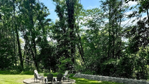 Un bain à remous dans un jardin luxuriant, agrémenté d’un mur en pierre et de mobilier d’extérieur.