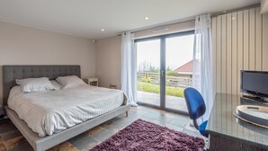 A bedroom with a bed, a desk with a chair, and a large sliding glass door leading to a balcony. - Bed & breakfast on a hillside with direct access to Colmar (Niedermorschwihr)
