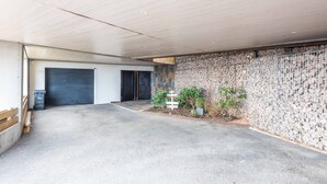 A covered parking area with a concrete floor, two doors, and a stone wall with a grid pattern. - Bed & breakfast on a hillside with direct access to Colmar (Niedermorschwihr)