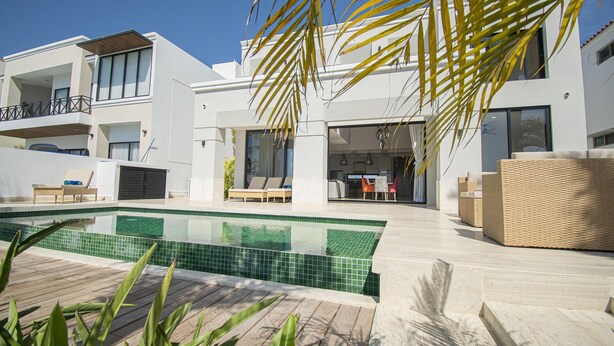 Ein modernes Wohngebäude mit Schwimmbad, Außenbereich mit Sitzgelegenheiten und einer Terrassenfläche.
