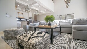 Ein modernes Wohnzimmer mit einem grauen Sofa, einem Couchtisch und einem gemusterten Teppich.