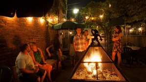 Un área de estar al aire libre con paredes de ladrillo, una chimenea y luces colgantes.