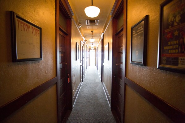 Un pasillo de hotel con cuadros en las paredes, piso alfombrado y puertas a ambos lados.