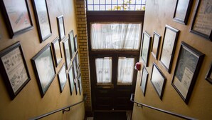 Una escalera con cuadros enmarcados en las paredes, que conduce a una puerta con ventanal.