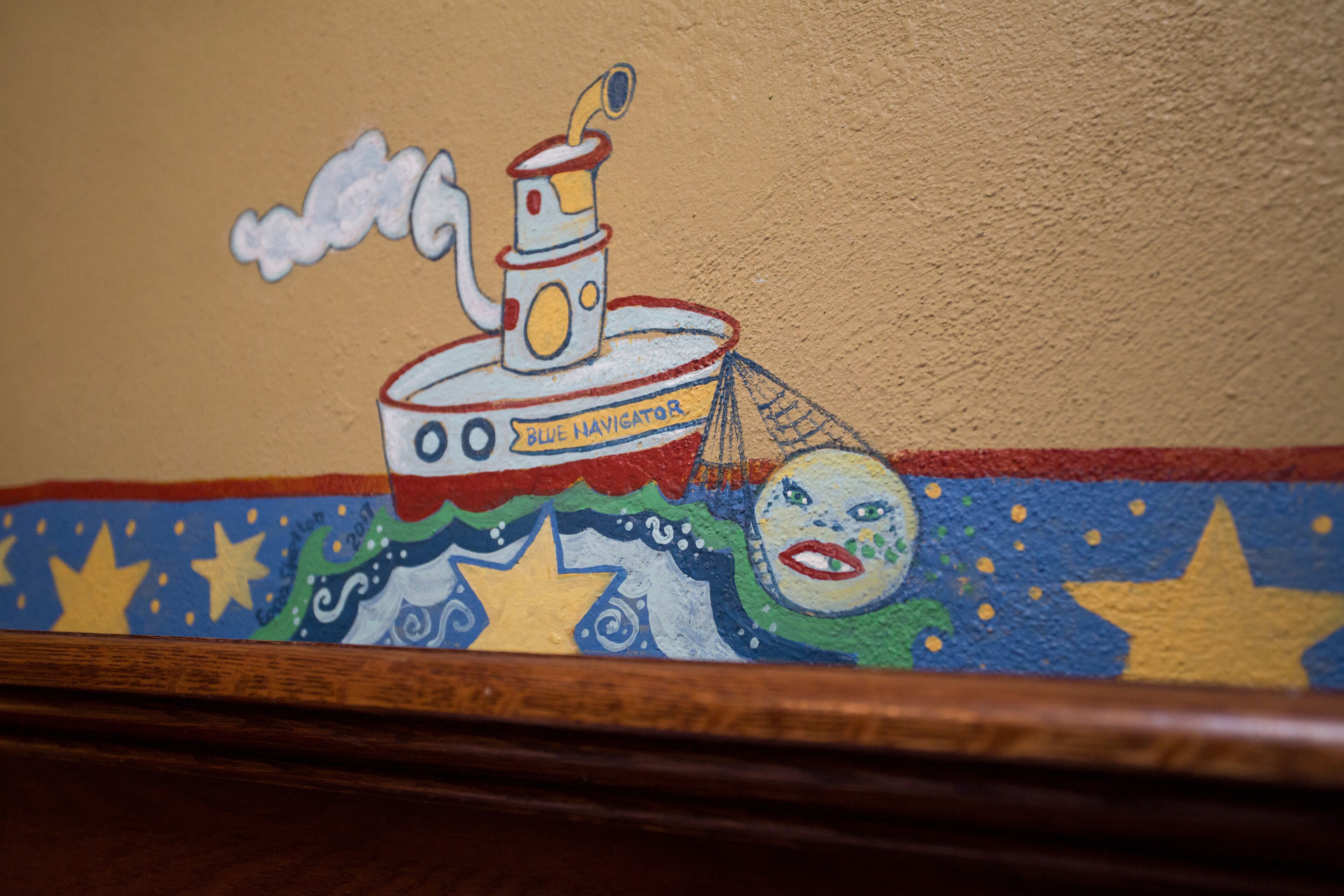 Un mural que muestra un barco con la inscripción 'Blue Navigator' en una pared.
