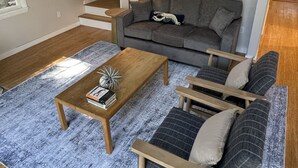 A modern living room with a sofa, a coffee table, and a lamp. - Into the Woods (Southwest Harbor)