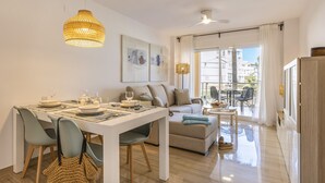 A modern living room with a dining area, a sofa, and a balcony with a view. - Golden Paradise Mar (Javea / Xàbia)