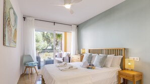 A bedroom with a bed, bedside table, chair, and a view of the outdoors. - Golden Paradise Mar (Javea / Xàbia)