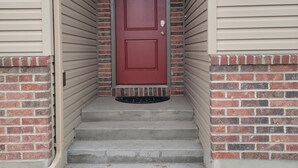 A red door with a small window above it, flanked by beige siding and brick accents. - Affordable Gathering Place-90 minutes to Yellowstone (Idaho Falls)