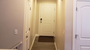 A narrow hallway with wooden flooring, white walls, and a white door at the end. - Affordable Gathering Place-90 minutes to Yellowstone (Idaho Falls)