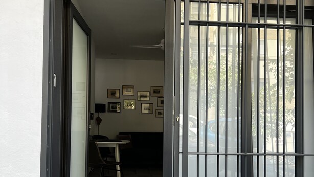 Un hall d’entrée moderne avec une porte coulissante en verre, un sol carrelé et un espace repas bien visible, comprenant des chaises et une table.