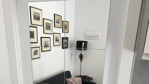 Un salon moderne avec un canapé gris foncé, un lampadaire noir et un miroir mural qui reflète la pièce.