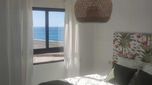 Un dormitorio con un ventanal que ofrece vistas a la playa y al océano.