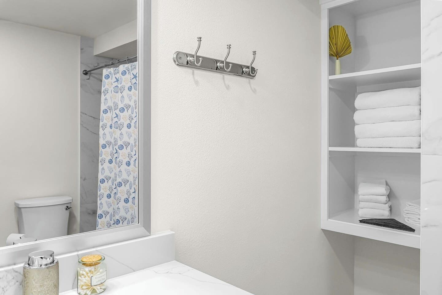 Een badkamer met toilet, douchegordijn, handdoekrek en een plank met opgevouwen handdoeken.