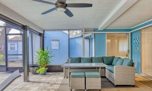 A covered patio with a ceiling fan, a sectional sofa, a dining table, and potted plants. - Siesta Key FL: Heated Pool, Beaches, Family Fun (Sarasota)