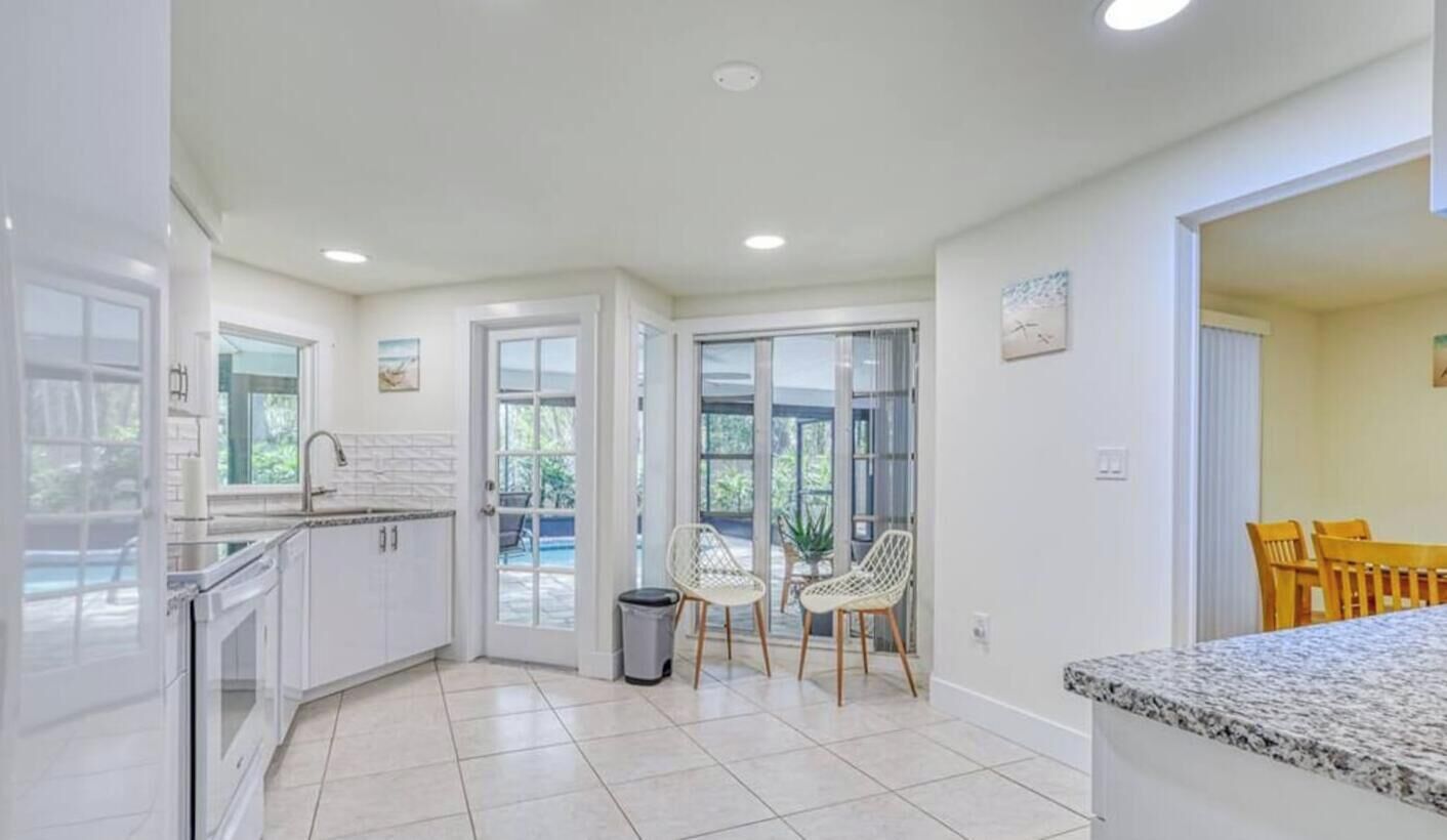 A modern kitchen with white cabinets, a granite countertop, and a view of the outdoors.