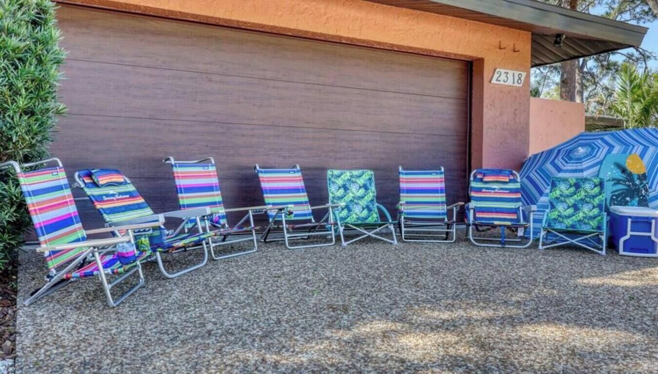 A row of beach chairs with colorful striped cushions in front of a garage door.
