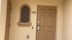A beige house with a brown door, number 433, a small window, and a welcome mat. - Regal Palms Resort Oasis (Davenport)