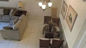 A living room with a sofa, a dining table with chairs, a chandelier, and framed pictures on the wall. - Regal Palms Resort Oasis (Davenport)