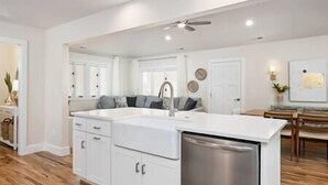 Una cocina amplia con armarios blancos, lavavajillas de acero inoxidable y ventilador de techo.