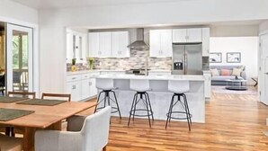 Una cocina moderna con armarios blancos, una isla central con taburetes y un protector contra salpicaduras de piedra.