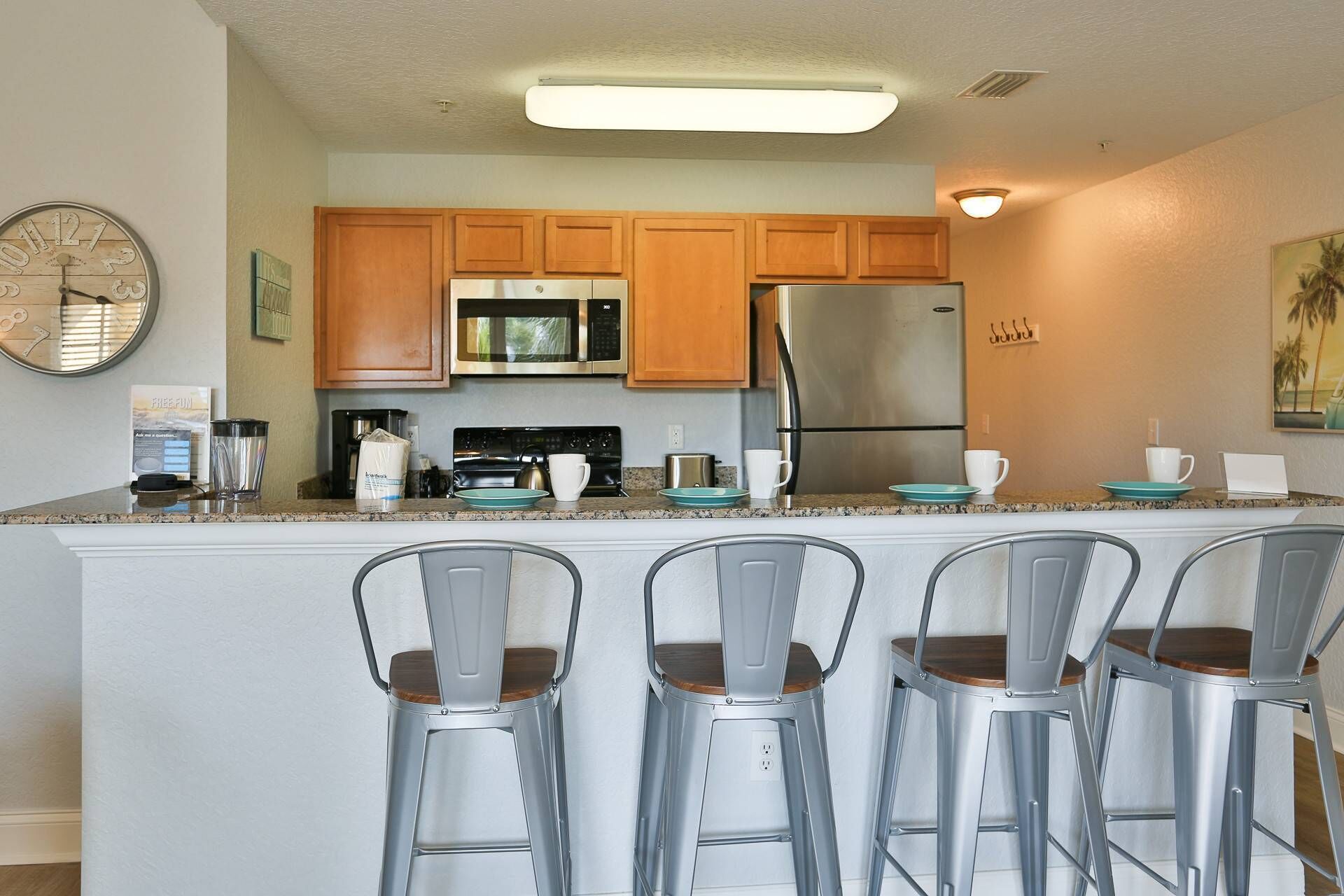 A modern kitchen with wooden cabinets, stainless steel appliances, and a central island with bar stools.