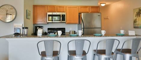 A modern kitchen with wooden cabinets, stainless steel appliances, and a central island with bar stools.