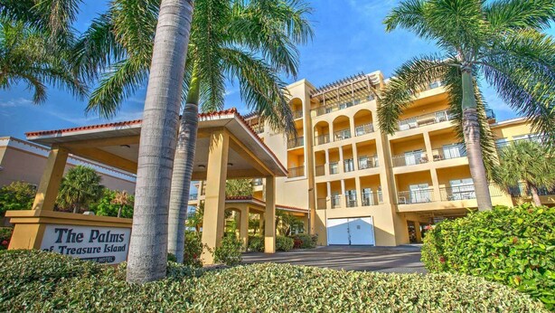 Un hotel con ingresso coperto, palme e un cartello con su scritto "The Palms of Treasure Island".
