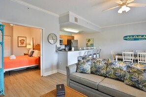 Ein kompakter Wohnraum mit Küchenzeile, Essbereich und einem Schlafzimmer mit orangefarbenem Bett.