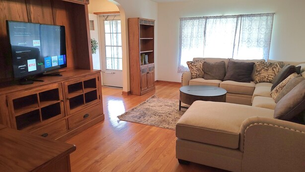 A living room with a wooden entertainment center, a beige sofa, and a television displaying streaming services.