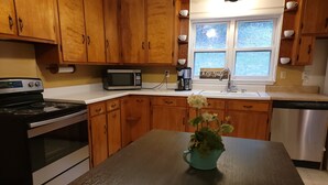 A kitchen with wooden cabinets, a microwave, a stove, a sink, and a dishwasher.