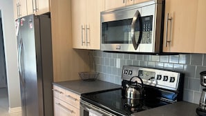 Una cocina moderna con electrodomésticos de acero inoxidable, armarios de madera y salpicadero de azulejos.