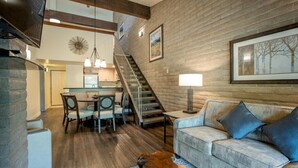 A spacious living area with a wooden floor, a sofa, a coffee table, and a staircase leading to an upper level. - Discover Vail's Best Kept Secret. Great family location. Sleeps up to 8. (Vail)