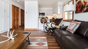 A modern living room with a leather sofa, wooden coffee table, and a colorful rug.
