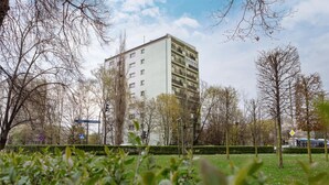 Ein mehrgeschossiges Gebäude mit Balkonen, umgeben von Bäumen und einer Grünfläche.