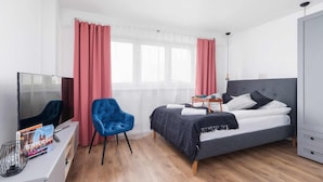 Ein modernes Hotelzimmer mit Bett, Fernseher, Schreibtisch und Stuhl.
