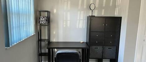 Um quarto com escrivaninha, cadeira e um armário de arquivos preto.